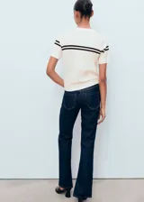 Jersey de punto fino color crema con cuello redondo, manga corta y diseño de rayas horizontales oscuras en el pecho.