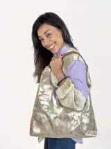 Bolso dorado tipo tote bag de cuero genuino, con asas de cuero marrón y sobre interno extraíble.