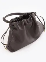 Cartera tipo shopper de cuero vacuno color tostado, con formato amplio, fruncido superior y cordones ajustables a los lados. Cuenta con tiras finas para llevar al hombro y sutil grabado de la marca en el frente.