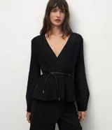 Cardigan de punto color negro con escote en V profundo, mangas largas y bajo con diseño peplum. Incluye un cinturón fino de material sintético con punteras metálicas para ajustar a la cintura.