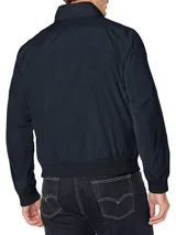 Campera bomber Tommy Hilfiger azul marino con cuello alto, cierre frontal con cremallera, dos bolsillos laterales con cremallera, puños y bajo elásticos. Tiene el logo de Tommy Hilfiger bordado en el pecho y un parche con el logo en la manga izquierda. El interior del cuello tiene detalles en rojo, blanco y azul.