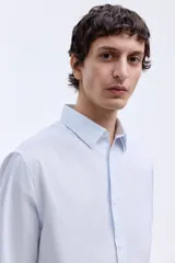 Camisa de corte entallado con cuello inglés, canesú en la espalda y mangas largas con puños ajustables. Presenta un diseño de rayas verticales finas y un bajo levemente redondeado.
