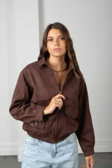 Campera corta de gamuza color marrón, con cierre frontal, cuello camisero y bolsillos frontales con solapa.