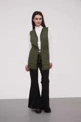 Chaleco largo sin mangas de tejido de punto color negro, con capucha y lazo ajustable en la cintura. Presenta bolsillos frontales y diseño abierto.