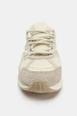 Zapatilla deportiva estilo running con combinación de materiales y detalles en tonos verdes. Presenta puntera redonda, tirador trasero y suela con relieve.