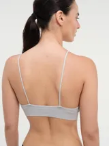 Bralette sin costuras, color gris claro, con tirantes finos ajustables y banda inferior ancha acanalada.