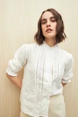 Camisa blanca de manga 3/4 confeccionada en algodón liviano con diseño calado y detalles de encaje en el frente. Cuello con volados.