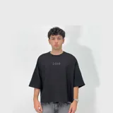 Remera negra de corte boxy fit y tejido grueso, con mangas 3/4 y diseño minimalista que incluye el número "1999" estampado en el pecho en tono sutil.