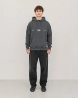 Canguro con capucha y bolsillo frontal tipo canguro, en color gris lavado. Presenta estampado gráfico pequeño en el pecho con el logo de la marca y detalles decorativos.