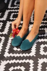 Ballerinas de terciopelo verde oscuro, de inspiración veneciana con ribetes en contraste y suela flexible.