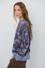 Buzo de tejido de punto con cuello redondo, mangas largas con puños acanalados y diseño estampado de flores en tonos rojos.
