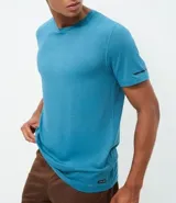 Remera deportiva de hombre con tecnología dry fit, cuello redondo y mangas cortas. Presenta un diseño minimalista con etiqueta aplicada en el dobladillo y detalles a contraste.