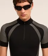 Remera negra ajustada al cuerpo, de cuello alto con cremallera y mangas cortas. Diseño seamless con estampa abstracta en tonos grises en hombros y laterales.