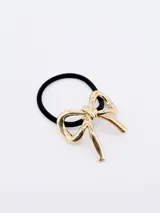 Colero elástico negro con aplique metálico en forma de moña color dorado.