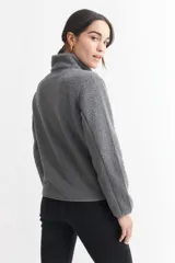 Campera negra de corderito con cuello alto, cierre frontal con cremallera, bolsillo de parche en el pecho y bolsillos laterales.