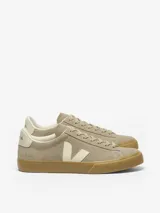 Championes Veja modelo Campo, confeccionados en gamuza color marrón con detalles en crema. Presentan la icónica V lateral, suela de goma color caramelo y cierre con cordones.