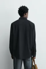 Camisa de corte relajado confeccionada en tejido ligero de lana y algodón. Presenta cuello con botones, manga larga con puños abotonados y cierre frontal de botones.