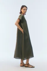 Vestido midi evasé color azul, confeccionado en lino, con escote redondo, mangas cortas con dobladillo vuelto y bolsillos laterales. Presenta un ruedo asimétrico, más largo en los laterales.