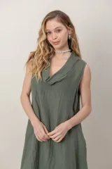Vestido midi de lino color verde militar, sin mangas, con escote buche y bolsillos laterales, de corte relajado y fluido.