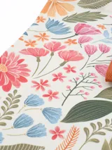 Tote bag plegable con estampado floral multicolor sobre base blanca, tiras de hombro y cinta de cierre en color tostado.