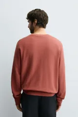 Sudadera de algodón color terracota, con cuello redondo, manga larga y puños y bajo acanalados. Presenta un efecto lavado que le da un aspecto desgastado.