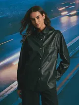 Sobrecamisa de cuero sintético en color negro, con cierre frontal de botones metálicos a presión, cuello clásico y un bolsillo frontal en el pecho.