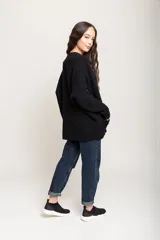 Sacón negro de lana merino, con mangas largas y bolsillos frontales.