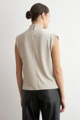 Blusa de lurex negra sin mangas, con cuello alto drapeado y detalle de pliegues frontales.