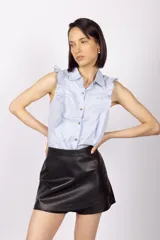 Blusa celeste sin mangas con cuello camisero y volados en los hombros.