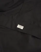 Rompeviento negro tipo canguro con capucha, cuello alto, cierre frontal oculto y bolsillo frontal tipo canguro con etiqueta de marca.
