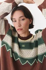 Buzo de tejido de punto con diseño geométrico y combinación de colores en contraste. Presenta cuello redondo, mangas largas y corte oversized.