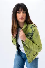 Campera de jean verde con efecto tie-dye en negro, de corte clásico, con cuello camisero, bolsillos con solapa en el pecho y cierre frontal con botones metálicos.