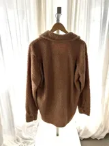 Camisa campera oversize de corderito color tostado con interior forrado en tela estampada, bolsillos frontales con solapa y cierre de botones.
