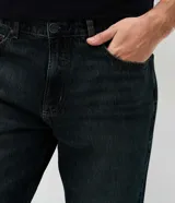 Pantalón de jean para hombre de corte recto y cintura media, confeccionado en algodón con lavado oscuro y efecto desgastado. Cuenta con cierre frontal con botón, pasadores para cinturón y bolsillos funcionales.