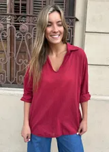 Camisa de fibrana color rojo burdeos, con cuello camisero, escote en V y mangas largas arremangadas.