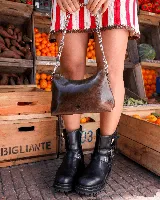 Cartera tipo media luna de cuero natural color marrón, con cierre superior y correa de cadena metálica plateada. Presenta el logo de la marca grabado en el frente.