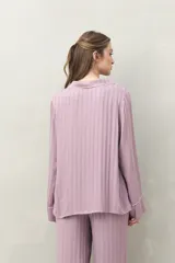 Camisa de pijama color blanco tiza con rayas verticales en relieve, de silueta clásica y caída fluida. Presenta cuello camisero, cierre frontal con botones y detalles de vivo rosado en cuello, puños y solapas.