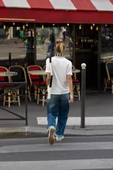 Camiseta negra de algodón, corte regular, con cuello redondo ribeteado en blanco y un bolsillo frontal con un broche metálico decorativo dorado.