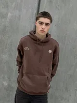 Canguro marrón con capucha ajustable con cordones, bolsillo tipo canguro y puños elásticos. Presenta un logo de un globo terráqueo y una flor bordados en el pecho.