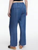 Pantalón de pierna recta y calce relajado, confeccionado en denim de lyocell con caída fluida. Presenta cintura elástica, bolsillos laterales y una pestaña lateral decorativa que recorre la prenda desde la cintura hasta el ruedo.