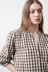 Camisa de algodón con estampado de cuadros vichy en tonos azul y blanco. Presenta escote en V con cierre frontal de botones, mangas largas con puños y un corte levemente holgado con frunces en hombros y espalda.