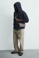 Bandolera rectangular color marrón oscuro, con solapa frontal y correa larga ajustable. Incluye un monedero pequeño en la correa.