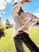 Camisa marrón de algodón con cuello clásico, cierre frontal con botones dorados y mangas largas abullonadas con puños elásticos.