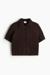 Saco de punto suave con cuello camisero y cierre frontal de botones. Presenta mangas cortas y terminaciones acanaladas en puños y ruedo.