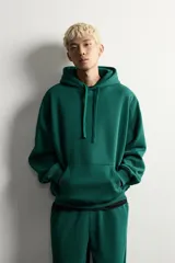 Sudadera con capucha de corte relajado, confeccionada en tejido de algodón con interior cepillado. Presenta manga larga, bolsillo frontal tipo canguro y acabados en rib en puños y bajo.