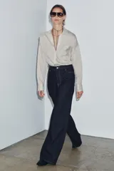 Jeans de tiro alto con corte wide leg y largo completo. Presenta diseño de cinco bolsillos, trabillas en la cintura y cierre frontal con cremallera y botón, con un acabado de efecto lavado.