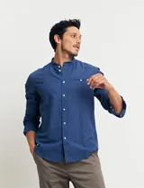 Camisa de cuello mao y manga larga, confeccionada en una mezcla de lino y algodón. Presenta un diseño de corte recto con botones en tono natural y un bolsillo pequeño en el pecho.