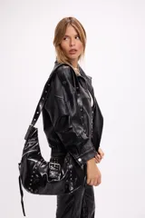 Campera estilo bomber oversize confeccionada en símil cuero negro con textura granulada. Presenta cuello alto con cierre frontal, hombreras marcadas, bolsillos laterales y cintura con elástico y cinto ajustable con hebilla metálica.