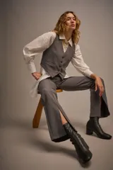 Pantalón gris de vestir con corte flare y abertura lateral en el ruedo.