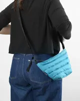 Bandolera celeste acolchada con correa larga ajustable de cinta negra.